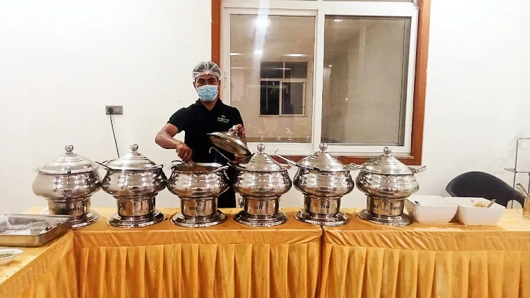 Catering staff serving from silver chafing dishes at a wedding
